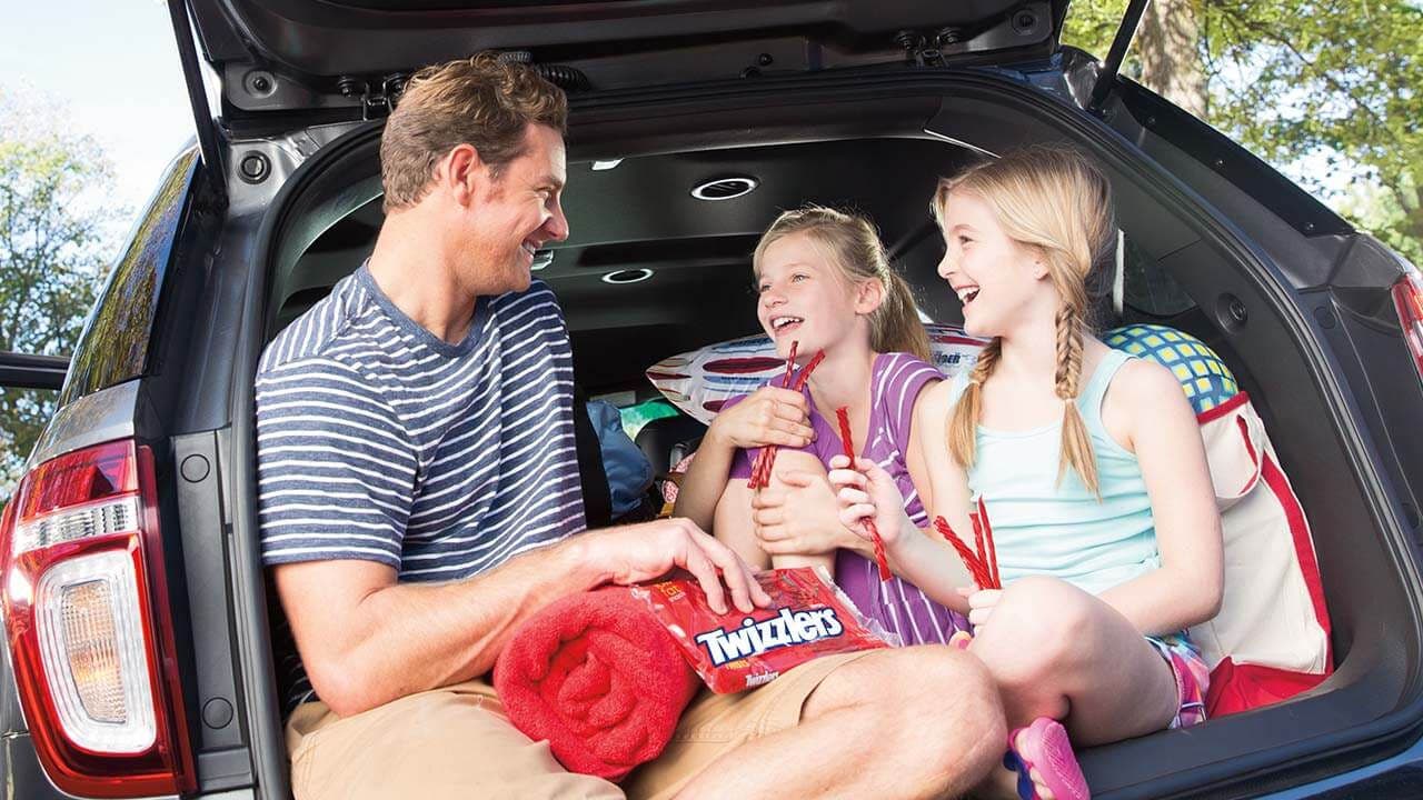 family sitting in the back of a car eating twizzlers strawberry twists