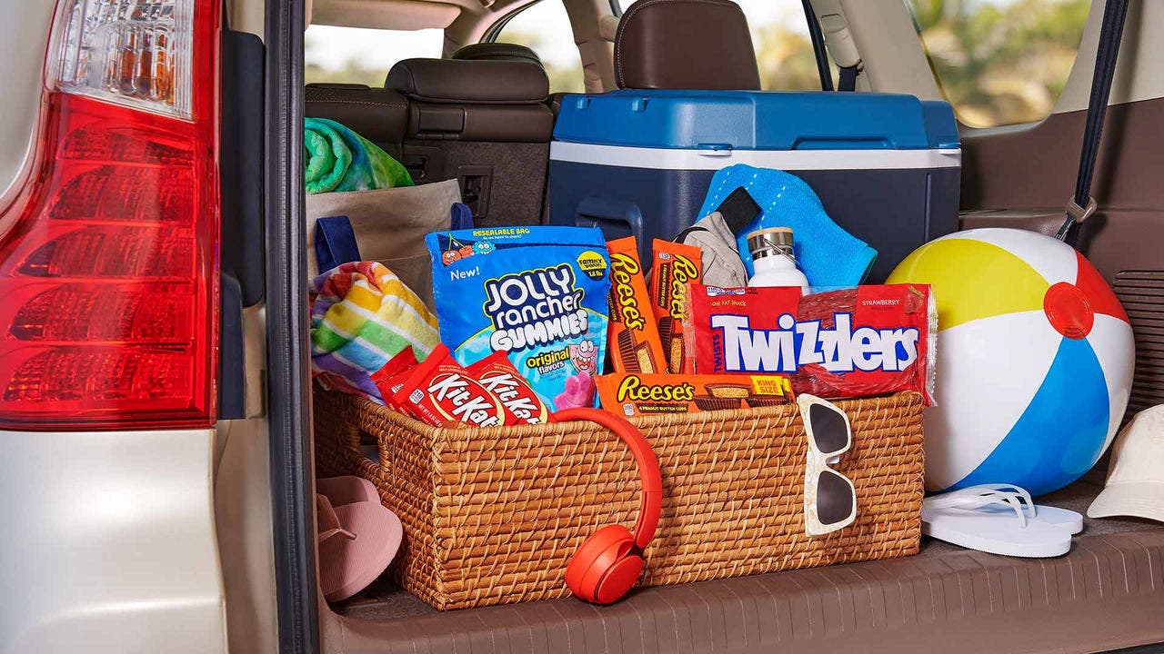 trunk filled with road trip essentials and basket full of assorted hersheys candies