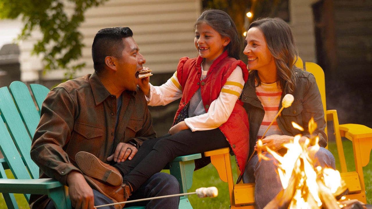 family enjoying smores outdoors around a campfire