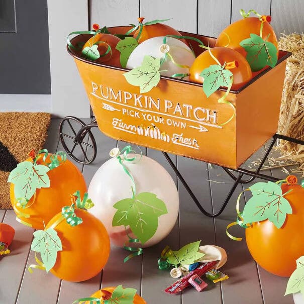 balloons decorated as pumpkins in a wheelbarrow