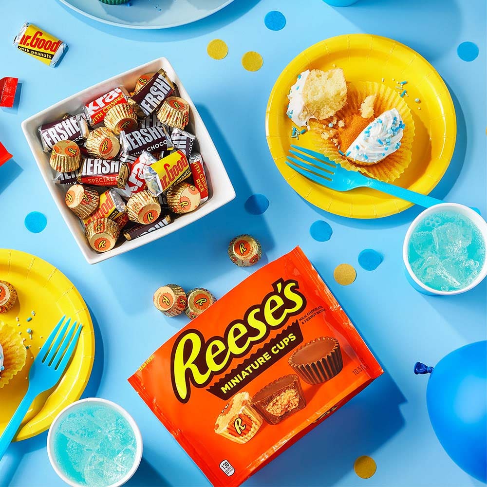 table filled with party decorations, candy, and freshly made cupcakes